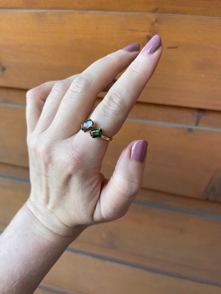 Marry me, John shown in pointer finger with tanzanite leaning towards sapphire in a toi et moi ring setting. 